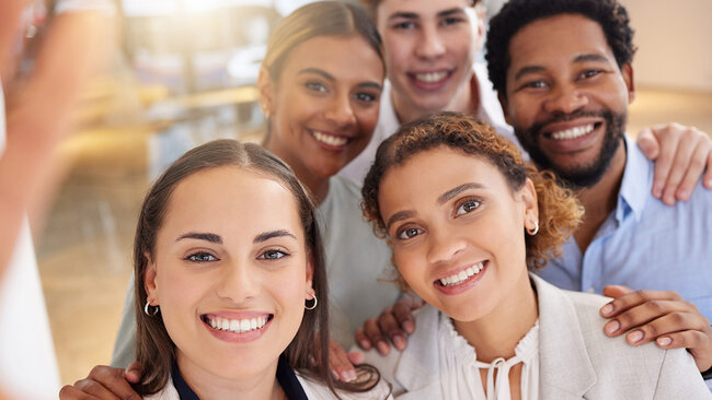 A group of smiling people taking a photo together, representing room reservations for multiple guests at Hôtels JARO.