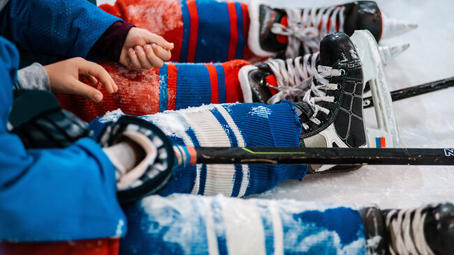 Équipements de hockey alignés sur le bord de la patinoire, mettant en valeur l'engagement des Hôtels JARO à accueillir des groupes sportifs avec des installations adaptées et un service personnalisé.